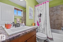 Bathroom featuring a built-in vanity with a drop-in sink, dark wood-finish cabinetry, and a stone-look countertop - 