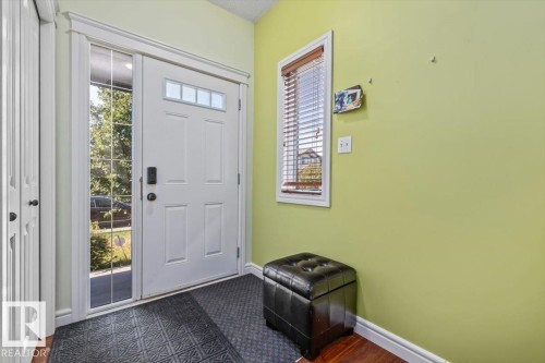 Entryway with a white paneled door featuring a transom window, sidelight, and matte black hardware - 11506 17 Avenue Sw, Edmonton, AB 