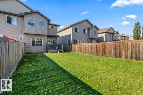 Expansive fenced backyard featuring a wooden deck with stairs, and a manicured lawn - 11506 17 Avenue Sw, Edmonton, AB 