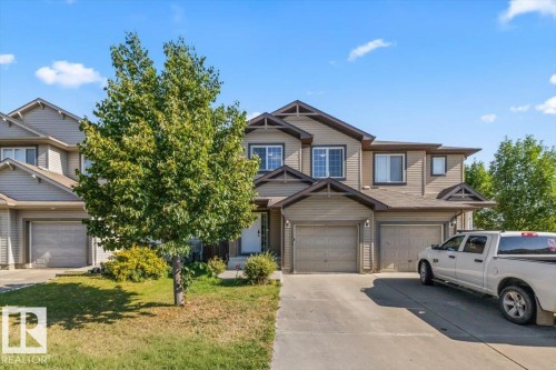 Multi-level exterior with horizontal siding, multiple windows, attached garage, and paved driveway - 11506 17 Avenue Sw, Edmonton, AB 
