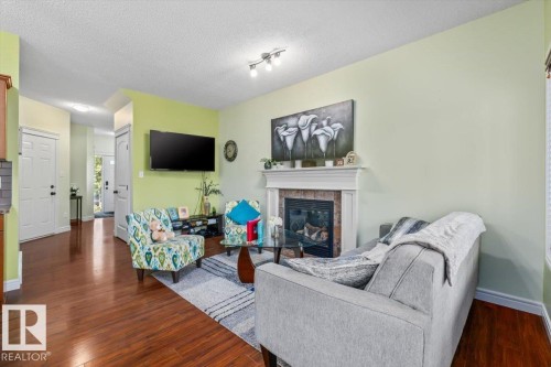 Wood-finish flooring throughout, with a decorative fireplace and white mantel - 11506 17 Avenue Sw, Edmonton, AB 