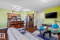 Wood-finish flooring throughout, track lighting, kitchen with wood cabinetry, stainless steel appliances, and a breakfast bar - 
