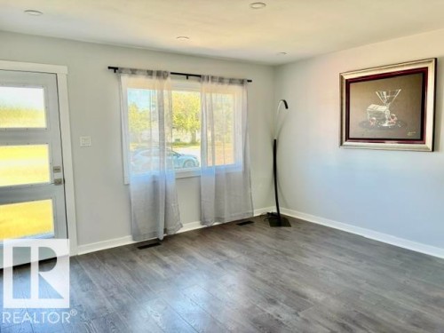 Wood-finish flooring, recessed lighting, and a window with a dark curtain rod - 5614 50 Street, Vegreville, AB 