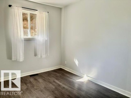 Wood-finish flooring with white trim and a single window - 5614 50 Street, Vegreville, AB 