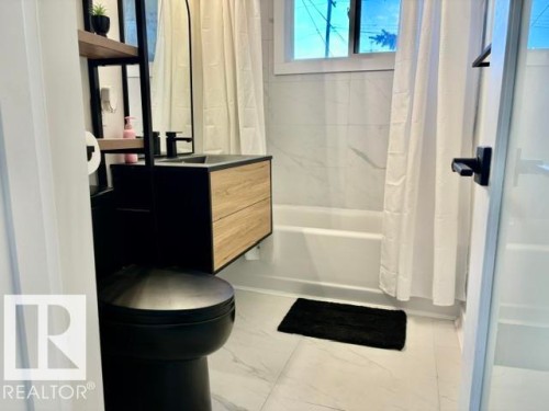 Floating wood-finish vanity with a dark basin and matte black faucet - 5614 50 Street, Vegreville, AB 