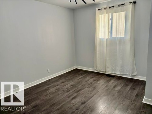 Recessed lighting, wood-finish flooring, light grey painted walls, white trim, and a window with sheer curtains - 5614 50 Street, Vegreville, AB 