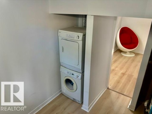 Stackable white laundry appliances with light wood-finish flooring - 5614 50 Street, Vegreville, AB 