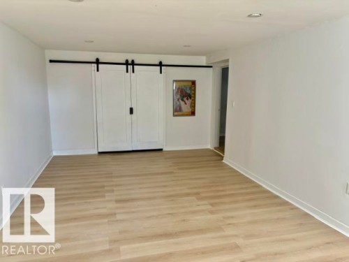 Wood-finish flooring, recessed lighting, white walls, and modern sliding barn doors with black hardware - 5614 50 Street, Vegreville, AB 
