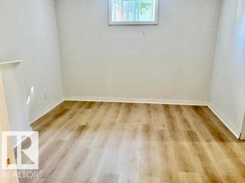 Wood-finish flooring with white baseboards, a single window, and light-colored walls - 5614 50 Street, Vegreville, AB 