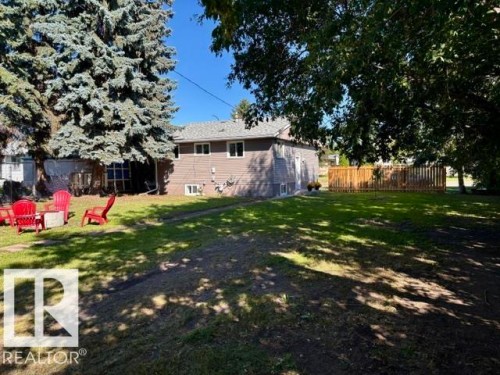 Expansive lawn area with a wood privacy fence and mature trees - 5614 50 Street, Vegreville, AB 