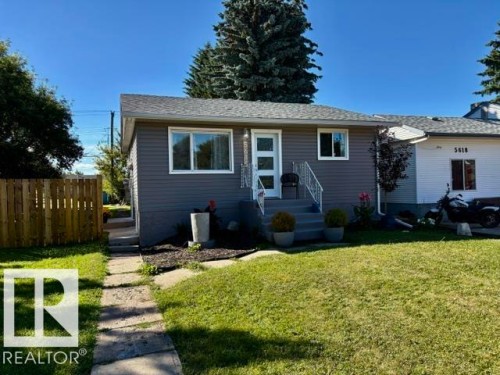 Gray siding exterior with white trim windows and a white front entry door - 5614 50 Street, Vegreville, AB 