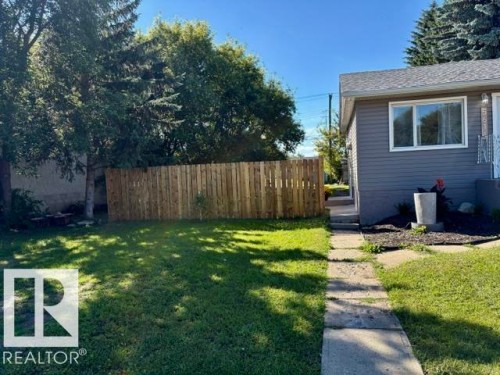 Manicured lawn with mature trees and a wood picket fence - 5614 50 Street, Vegreville, AB 