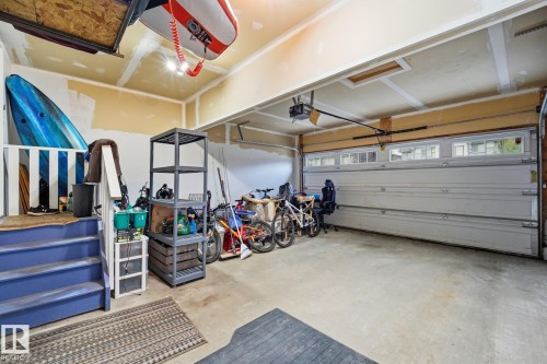 Garage space featuring a built-in overhead storage rack, concrete flooring, and an overhead garage door with upper window inserts - 20007 131 Avenue Nw, Edmonton, AB 