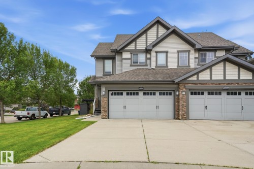 Multi-story exterior with light-colored siding, dark trim, stone accents, and a dual garage - 20007 131 Avenue Nw, Edmonton, AB 