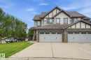 Multi-story exterior with light-colored siding, dark trim, stone accents, and a dual garage - 20007 131 Avenue Nw, Edmonton, AB 