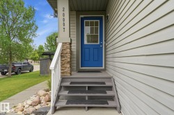 Entry featuring a vibrant blue door with upper lites, flanked by siding and a stone-accented column - 