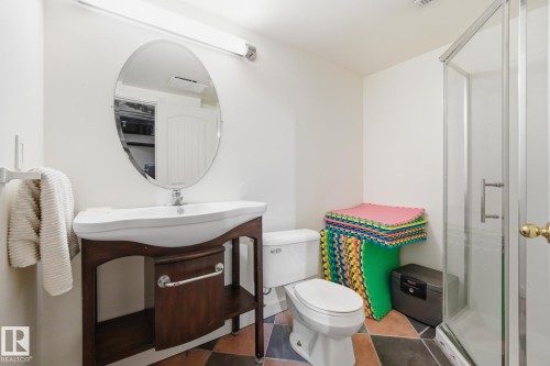 White vanity with a vessel sink, oval wall-mounted mirror, and glass-enclosed shower - 20007 131 Avenue Nw, Edmonton, AB 