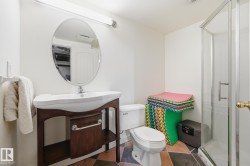 White vanity with a vessel sink, oval wall-mounted mirror, and glass-enclosed shower - 