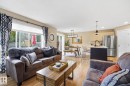 Open-concept living area featuring wood-finish flooring, sliding glass doors, a kitchen island with pendant lighting, and stainless steel appliances - 20007 131 Avenue Nw, Edmonton, AB 