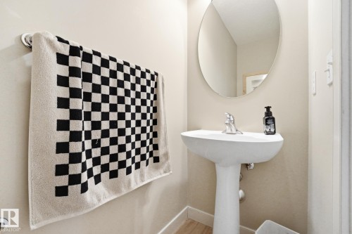 Pedestal sink with a polished chrome faucet, oval wall mirror, and light-toned wall paint - 20007 131 Avenue Nw, Edmonton, AB 