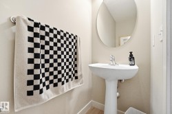 Pedestal sink with a polished chrome faucet, oval wall mirror, and light-toned wall paint - 