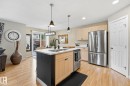 Kitchen with wood-finish flooring, light wood cabinetry, stainless steel appliances, and a central island with an integrated sink - 20007 131 Avenue Nw, Edmonton, AB 