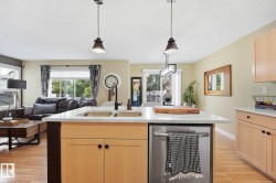 Kitchen island with a double basin sink, stainless steel appliances, and pendant lighting - 