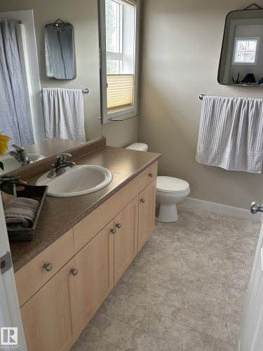 Bathroom featuring a single vanity with a countertop, integrated sink, and light wood-finish cabinetry - 20007 131 Avenue Nw, Edmonton, AB 