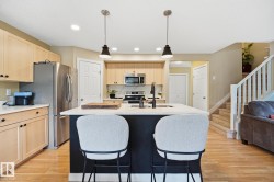 Kitchen featuring a center island with pendant lighting, stainless steel appliances, and light wood-finish cabinetry - 