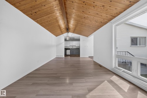 Vaulted wood-finish ceiling, light wood-finish flooring, white walls, and a large picture window - 155 Marlborough Place Nw, Edmonton, AB 