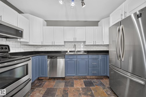 Kitchen featuring stainless steel appliances, white subway tile backsplash, two-tone cabinetry, and a double basin sink - 155 Marlborough Place Nw, Edmonton, AB 