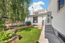 Manicured lawn with wood-framed garden beds, mature trees, and a private wooden fence - 155 Marlborough Place Nw, Edmonton, AB 