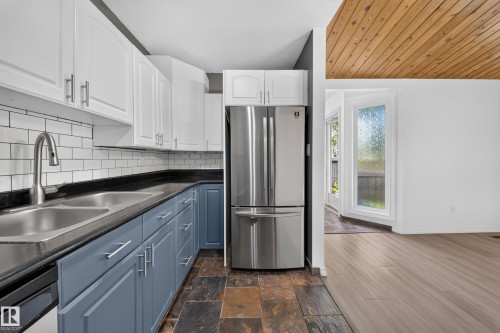 Kitchen featuring white upper cabinetry, blue lower cabinetry, stainless steel appliances, and tile flooring - 155 Marlborough Place Nw, Edmonton, AB 