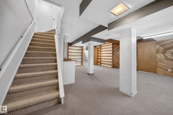 Carpeted staircase with white railings, recessed lighting, built-in shelving, wood-paneled accent wall, and neutral carpeting - 