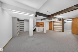 Spacious room with gray carpeting, extensive built-in shelving, wood-paneled accents, and exposed ceiling beams - 