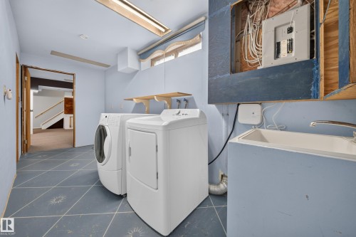 Laundry area featuring a utility sink, wall-mounted shelving, and tiled flooring - 155 Marlborough Place Nw, Edmonton, AB 