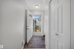 Foyer featuring slate tile flooring, a white paneled entry door with an arched glass insert, and a flush mount ceiling light - 