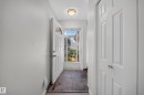 Foyer featuring slate tile flooring, a white paneled entry door with an arched glass insert, and a flush mount ceiling light - 155 Marlborough Place Nw, Edmonton, AB 