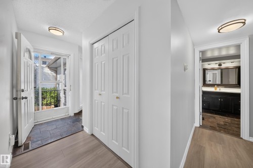 Entry foyer featuring slate-style tile flooring, wood-finish flooring, and white bi-fold closet doors - 155 Marlborough Place Nw, Edmonton, AB 