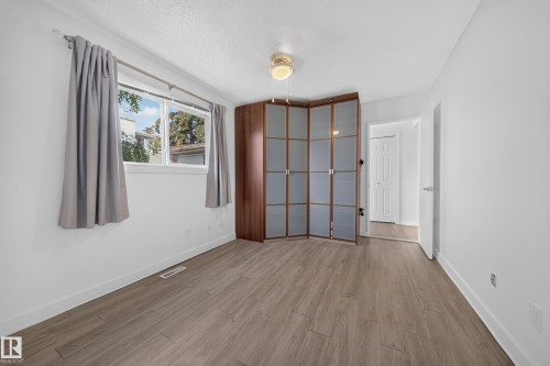 Wood-finish flooring, white walls, ceiling fan, and a built-in wardrobe with frosted panels - 155 Marlborough Place Nw, Edmonton, AB 