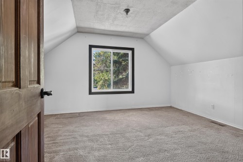 Vaulted ceiling with textured finish, wood-panel door with dark hardware, and a window with dark trim - 13351 109A Avenue Nw, Edmonton, AB 