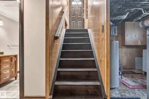 Wood-paneled staircase with dark wood-finish treads and a dark handrail - 13351 109A Avenue Nw, Edmonton, AB 