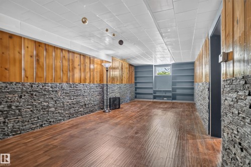 Wood-finish flooring, stone accent wall, wood paneling, and built-in shelving - 13351 109A Avenue Nw, Edmonton, AB 