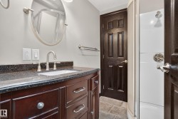 Cherry wood-finish vanity with a dark speckled countertop, undermount sink, and brushed nickel faucet - 