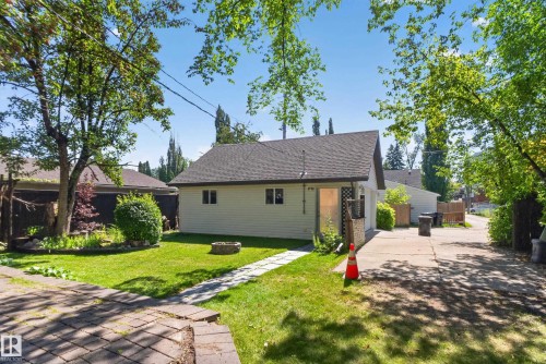Detached garage with a dark shingle roof, concrete driveway, and a stone-edged fire pit - 13351 109A Avenue Nw, Edmonton, AB 
