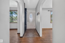 Arched doorways frame the entry, featuring a front door with an oval stained-glass insert, tile flooring, and a built-in storage unit - 