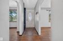 Arched doorways frame the entry, featuring a front door with an oval stained-glass insert, tile flooring, and a built-in storage unit - 13351 109A Avenue Nw, Edmonton, AB 