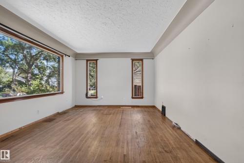 Wood-finish flooring with a large picture window and two vertical windows - 13351 109A Avenue Nw, Edmonton, AB 