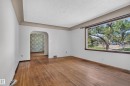 Expansive window with dark trim, wood-finish flooring, light-toned walls, and an arched doorway - 13351 109A Avenue Nw, Edmonton, AB 