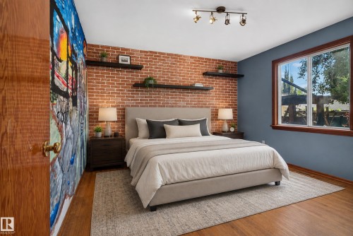 Exposed brick accent wall with floating shelving, wood-finish flooring, and a large window with wood trim - 13351 109A Avenue Nw, Edmonton, AB 